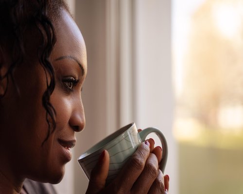 Man drinking coffee looking through the window peacefully
